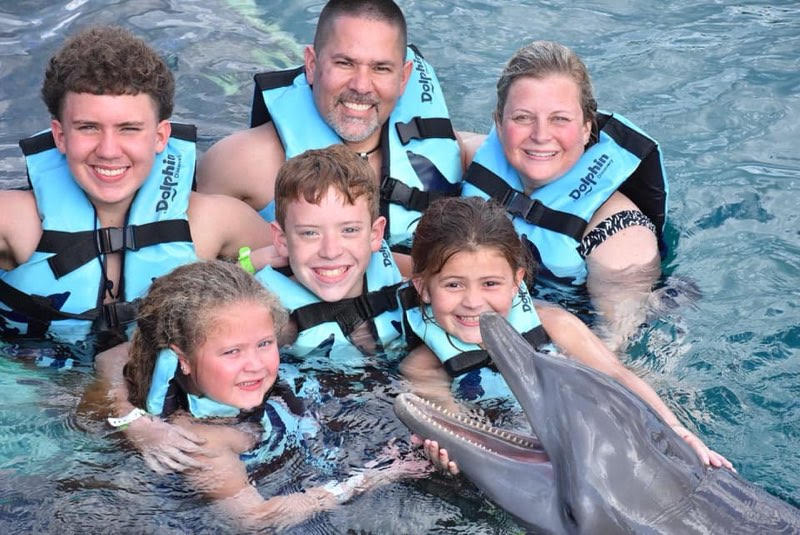 Louis with his family swimming with a dolphin